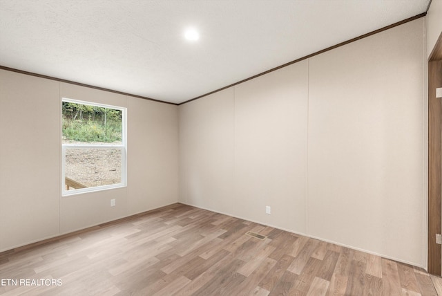 unfurnished room with light hardwood / wood-style flooring, a textured ceiling, and ornamental molding