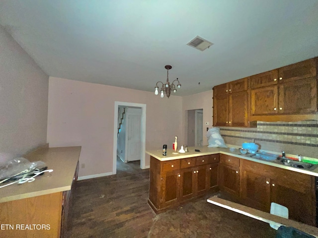 kitchen with kitchen peninsula, dark hardwood / wood-style flooring, decorative light fixtures, sink, and a chandelier