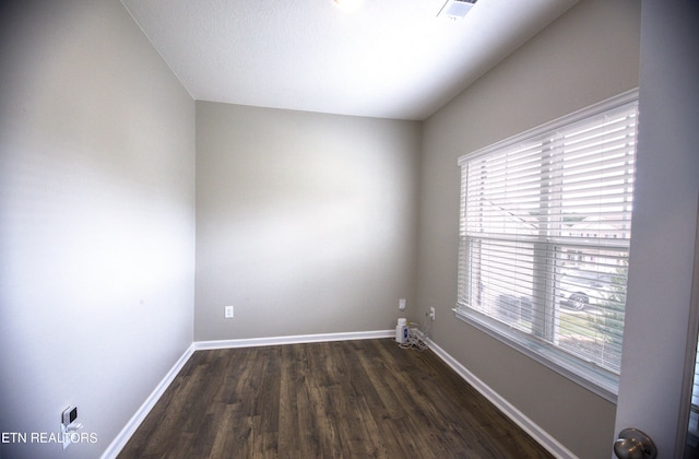 spare room featuring dark wood-type flooring and a healthy amount of sunlight