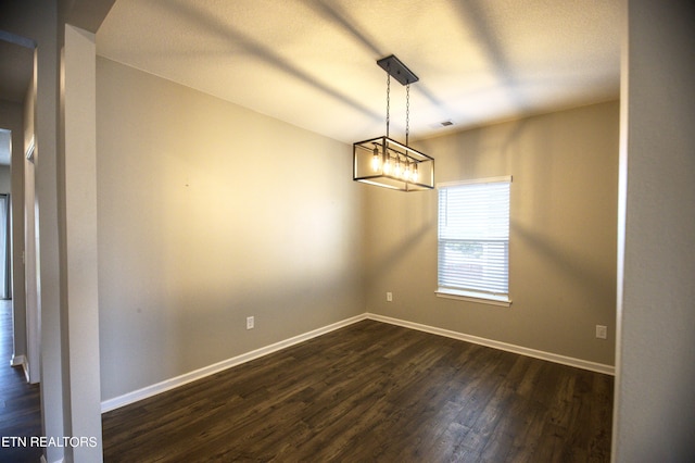 unfurnished room with a chandelier and dark hardwood / wood-style floors