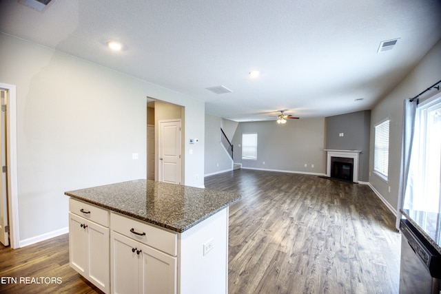 kitchen featuring dark stone countertops, dark wood-type flooring, a healthy amount of sunlight, and white cabinetry