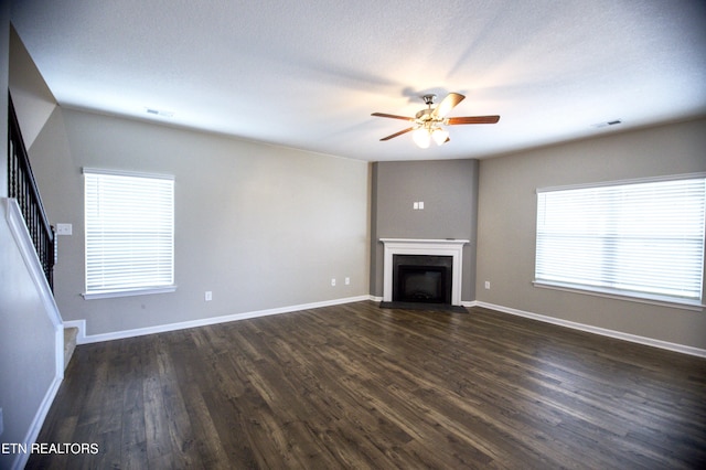 unfurnished living room featuring ceiling fan, dark hardwood / wood-style floors, a healthy amount of sunlight, and a textured ceiling