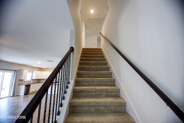 staircase with wood-type flooring and sink