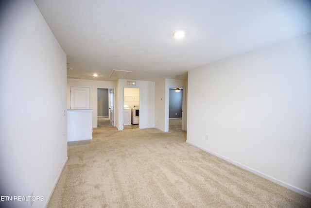 empty room featuring washer and clothes dryer and light colored carpet