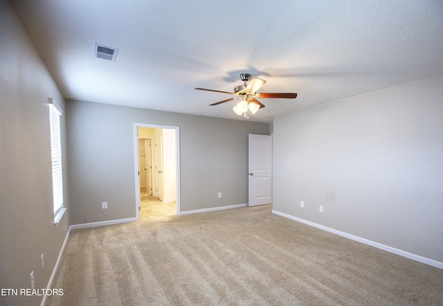 spare room with ceiling fan, a textured ceiling, and light carpet