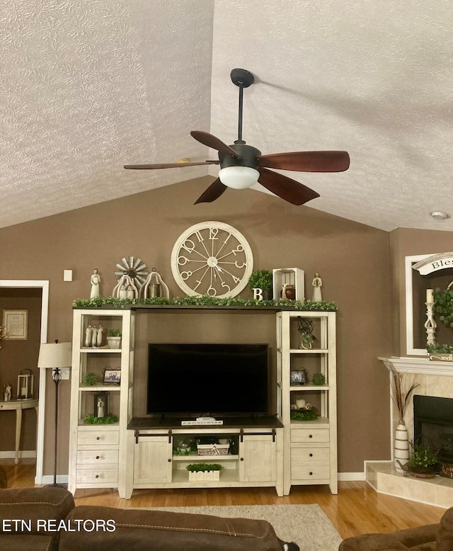 unfurnished living room featuring ceiling fan, a textured ceiling, lofted ceiling, and a fireplace