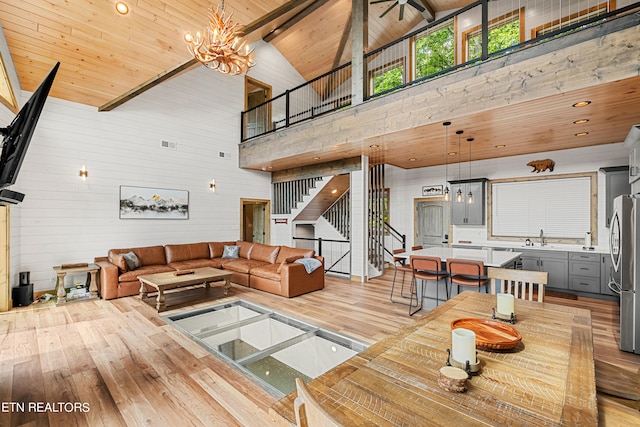 living room with wood ceiling, high vaulted ceiling, light wood-type flooring, beam ceiling, and an inviting chandelier