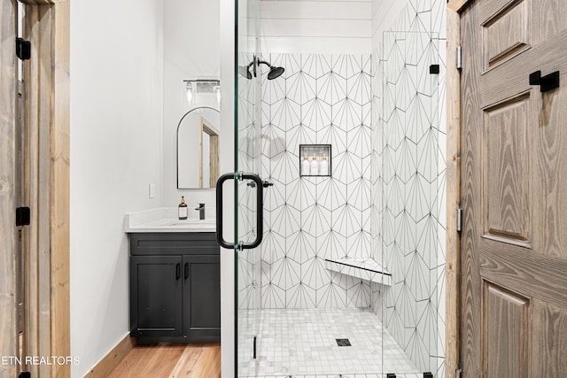 bathroom with hardwood / wood-style flooring, vanity, and a shower with shower door