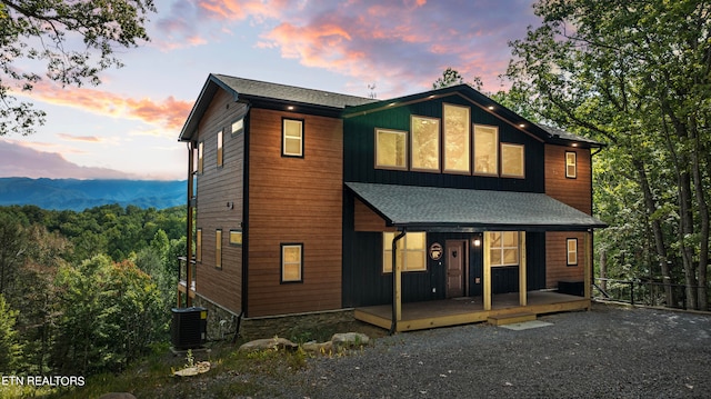 back house at dusk featuring a porch