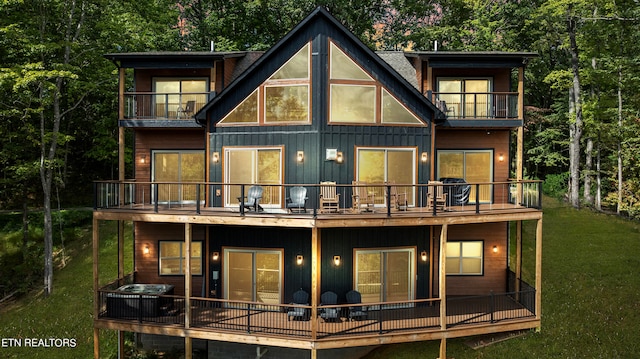 rear view of property featuring a balcony and a lawn