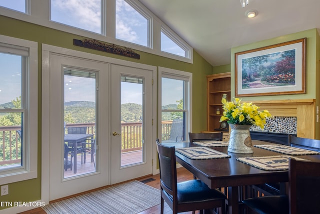 dining space with french doors, light wood-type flooring, vaulted ceiling, and a wealth of natural light