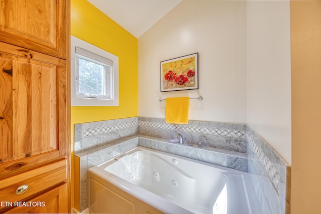 bathroom featuring lofted ceiling and a bath