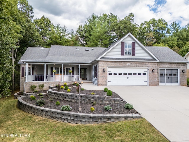 view of front of home with a garage, a front yard, and covered porch