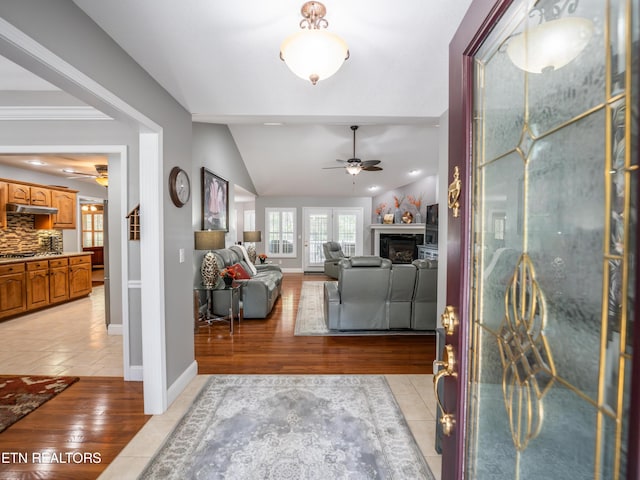 foyer with light wood-type flooring, lofted ceiling, ornamental molding, and ceiling fan