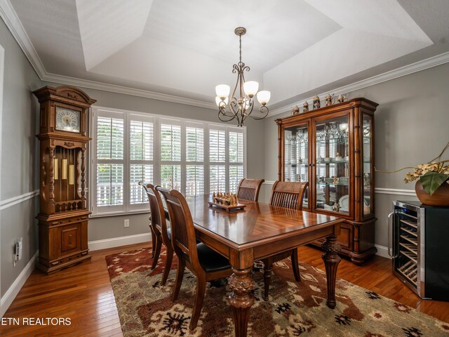 dining space with ornamental molding, beverage cooler, a tray ceiling, and dark hardwood / wood-style flooring