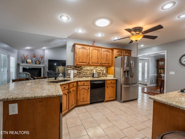 kitchen featuring dishwasher, light stone counters, stainless steel fridge with ice dispenser, sink, and ceiling fan