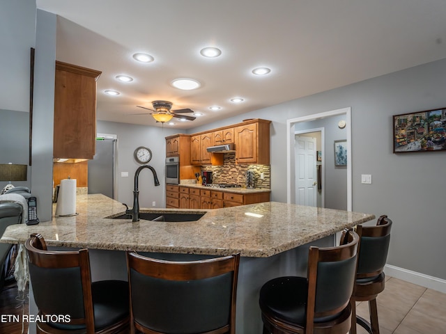 kitchen with sink, a breakfast bar area, kitchen peninsula, stainless steel appliances, and ceiling fan