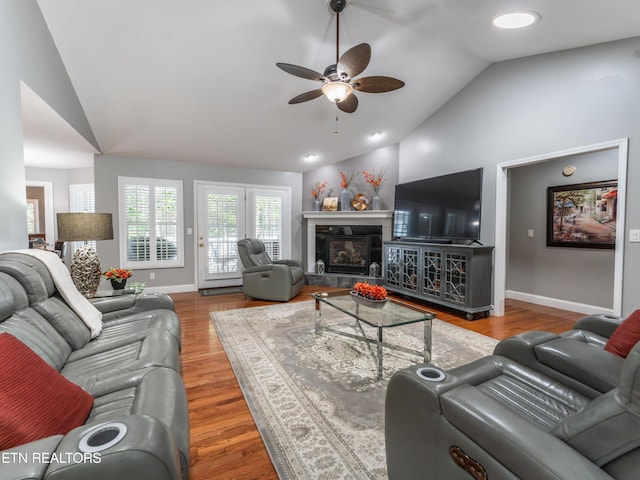 living room with ceiling fan, vaulted ceiling, and wood-type flooring