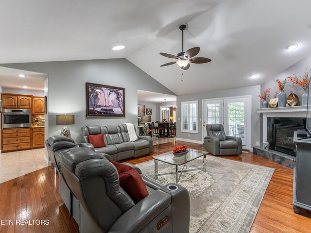 living room with ceiling fan, light hardwood / wood-style flooring, a high end fireplace, and lofted ceiling