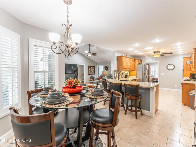 dining area featuring ceiling fan with notable chandelier, vaulted ceiling, and sink