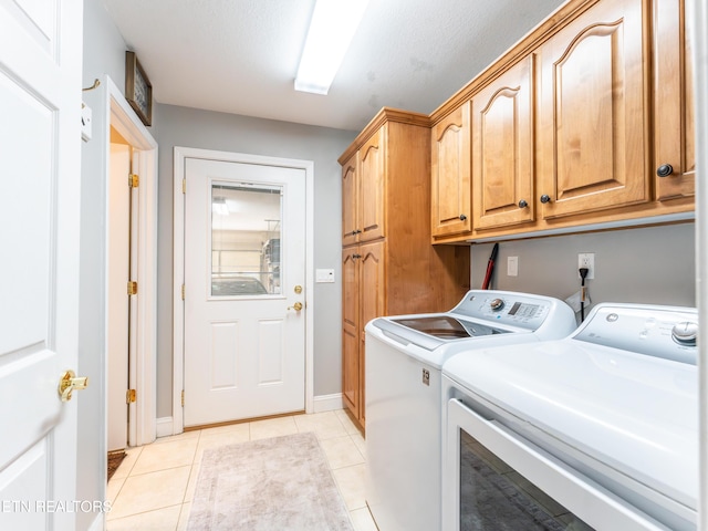 laundry room featuring cabinets, a textured ceiling, light tile patterned floors, and washing machine and dryer