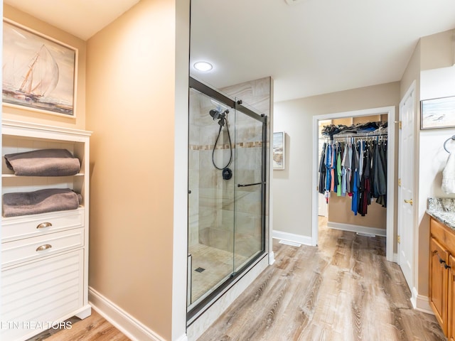 bathroom with walk in shower, vanity, and hardwood / wood-style flooring