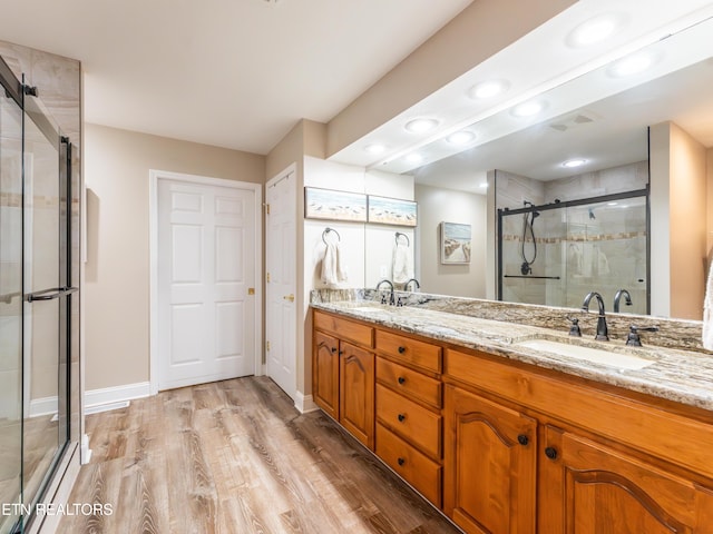 bathroom featuring hardwood / wood-style flooring, vanity, and a shower with door