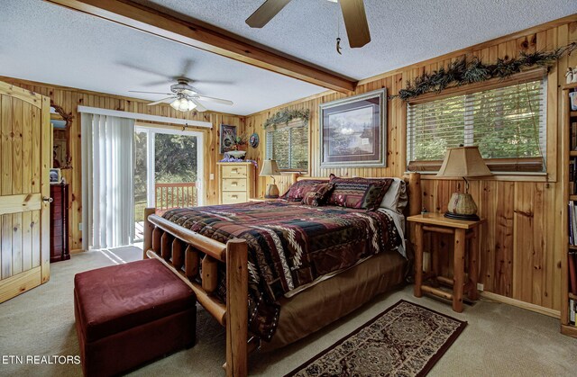 bedroom with ceiling fan, a textured ceiling, wood walls, and access to exterior