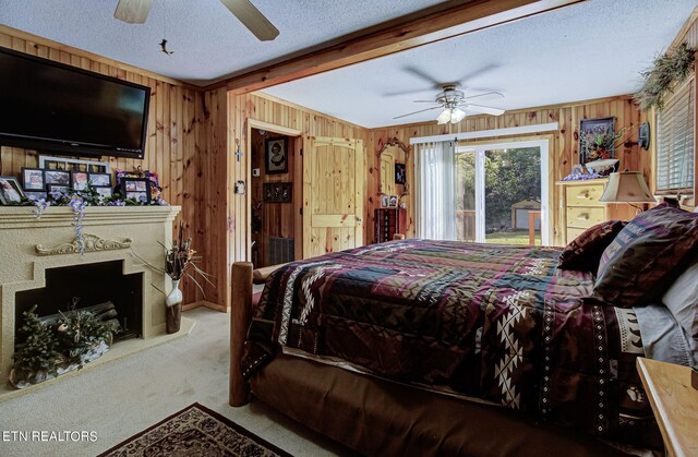 bedroom with ceiling fan, a textured ceiling, wood walls, and light carpet