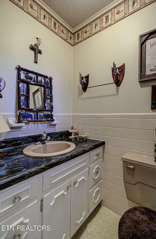 bathroom featuring vanity, a textured ceiling, tile patterned floors, tile walls, and toilet