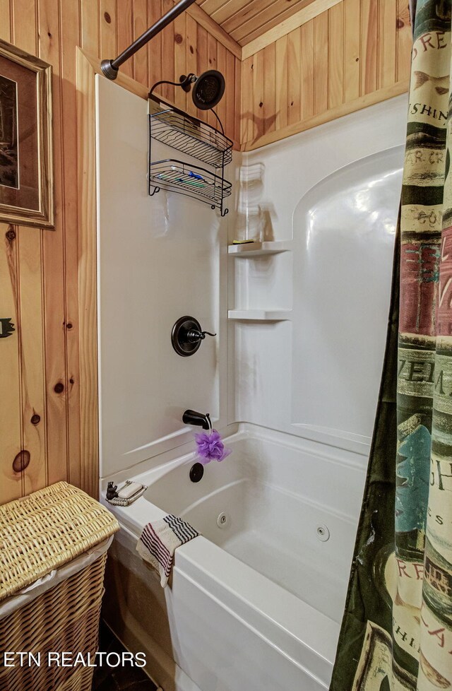 bathroom with wooden walls and shower / bath combo