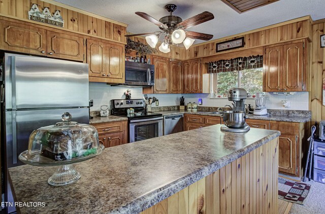 kitchen with ceiling fan, a textured ceiling, stainless steel appliances, and tasteful backsplash