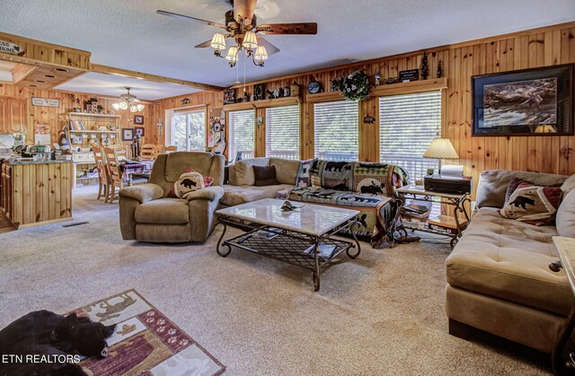 living room with wooden walls, ceiling fan, carpet flooring, and a textured ceiling