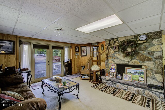 carpeted living room with wood walls, french doors, and a paneled ceiling