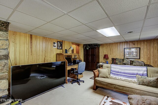 carpeted living room with a drop ceiling and wooden walls