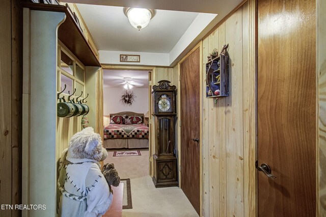 hallway with carpet floors and wood walls