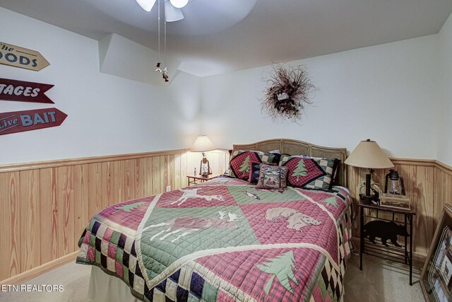 carpeted bedroom featuring wooden walls and ceiling fan