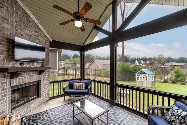 deck with ceiling fan, an outdoor brick fireplace, a lawn, and a storage unit