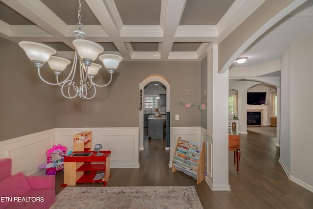 interior space with beamed ceiling, dark hardwood / wood-style floors, a notable chandelier, coffered ceiling, and ornamental molding