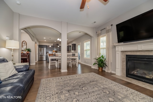 living room with ceiling fan, dark hardwood / wood-style flooring, and a tile fireplace