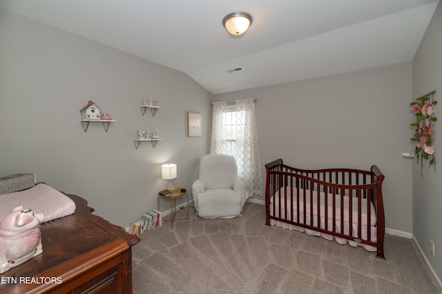 bedroom featuring lofted ceiling, a nursery area, and carpet floors