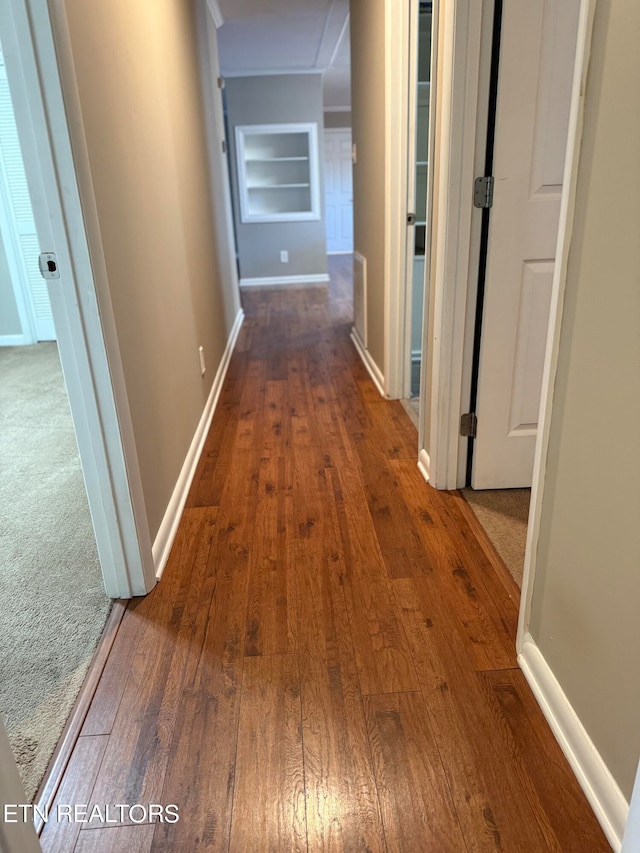 hallway featuring built in shelves and dark wood-type flooring