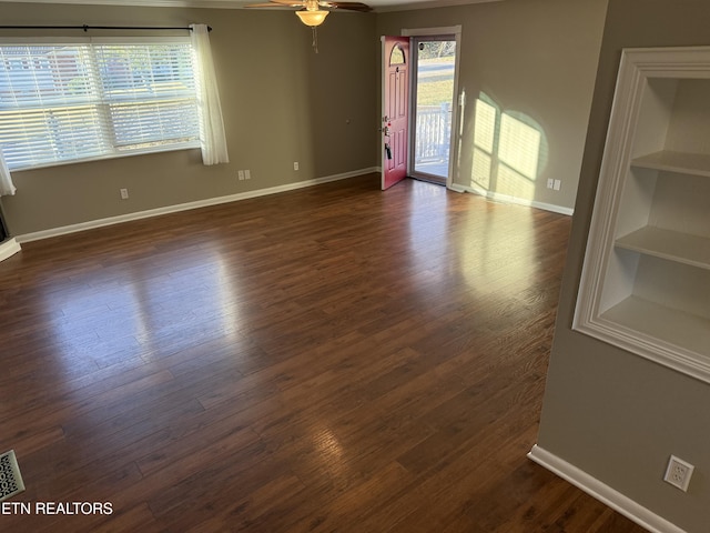 spare room with dark wood-type flooring, ceiling fan, and built in shelves