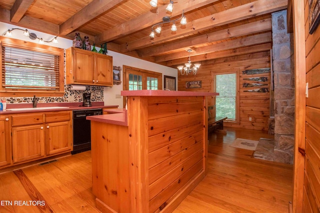 kitchen featuring pendant lighting, dishwasher, light hardwood / wood-style floors, and wood walls