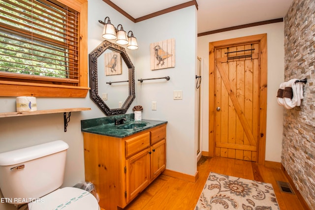 bathroom with vanity, ornamental molding, wood-type flooring, brick wall, and toilet