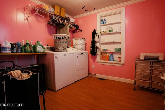 laundry area featuring wood-type flooring, washer and clothes dryer, and ornamental molding