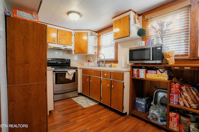 kitchen featuring tasteful backsplash, sink, light hardwood / wood-style flooring, and appliances with stainless steel finishes