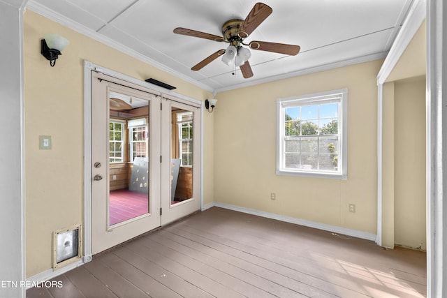 empty room with plenty of natural light, ornamental molding, ceiling fan, and hardwood / wood-style flooring