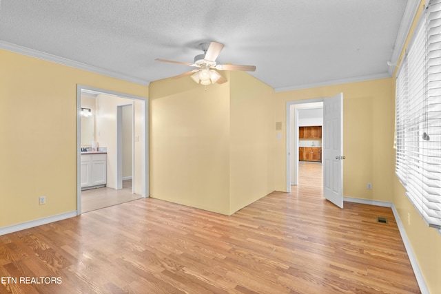 spare room with a textured ceiling, crown molding, ceiling fan, and light hardwood / wood-style flooring