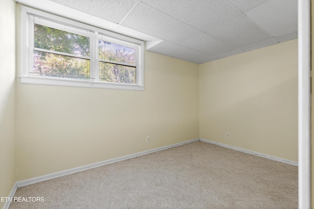 spare room featuring light carpet and a paneled ceiling